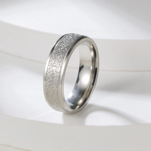 Detailed view of a 2mm silver matte stainless steel ring on a white tiered stand
