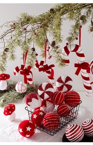 Detail of red and white candy cane ornaments and glittered baubles on a pine branch