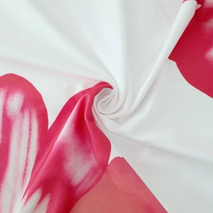 Detailed close-up of soft white fabric with vibrant red floral print and smooth texture