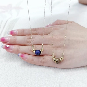 Detail of tiger eye and lapis lazuli pendants on gold beaded stainless steel necklaces
