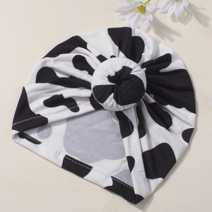 Infant knotted beanie featuring classic black and white cow print and donut knot design