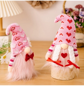 Detail view of pink Valentine's Day gnomes with knitted heart hats on wooden surface