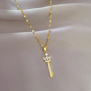 Detail of gold crown key pendant with sparkling zircons on a fine flat chain necklace