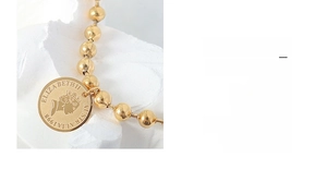 Macro shot of vintage 18K gold plated steel bead bracelet with Queen Elizabeth II coin charm