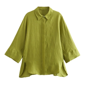 Dettaglio camicia di lino verde erba con spacco laterale e orlo irregolare su fondo bianco