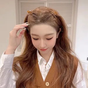 Set of two caramel brown bow-shaped hair clips in translucent resin worn by a model