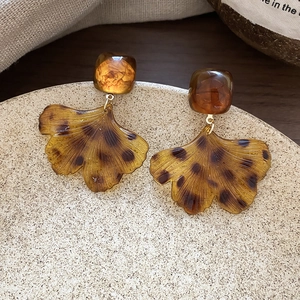 Vue détaillée des boucles d'oreilles feuille de ginkgo ambre sur plateau en céramique