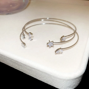 Detailed view of silver finish open bangles with star and droplet zircon inlays