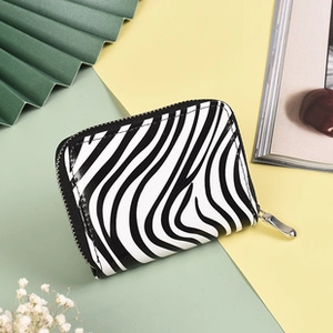 Macro detail of zebra print card holder with silver zipper on a minimalist background