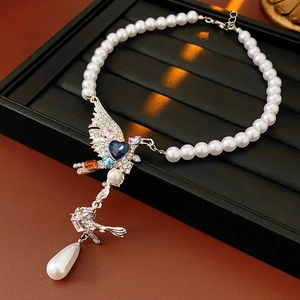 Détail du collier pendentif oiseau avec pierres précieuses et perle en forme de goutte