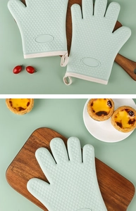 Close-up of light green silicone oven gloves with heart pattern and fabric cuffs