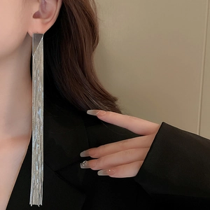 Close-up of elegant silver long tassel earrings with geometric triangle stud on model