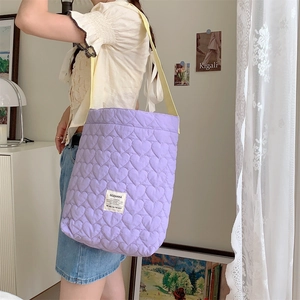 Detail of purple quilted tote bag with heart patterns and yellow contrast shoulder strap