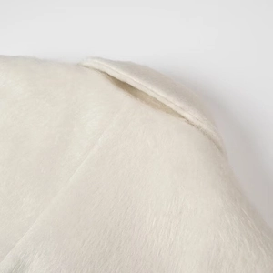 Detailed macro view of pure white plush faux fox fur texture on a loose-fitting lapel coat