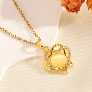 Collana doppia cuore dorata con pietra occhio di gatto e diamanti su sfondo di pietra