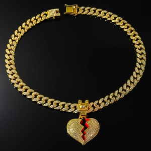 Close-up of hip hop gold Cuban chain with iced-out broken heart pendant on black background