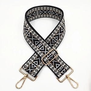 Detail of bohemian black and gold woven bag strap with geometric patterns and metal hooks