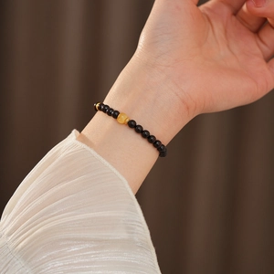 Detail of beaded sandalwood bracelet with amber bead and gold spacers on a female wrist