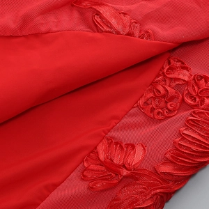 Détail d'une robe licou rouge avec broderie florale et tissu en tulle résille