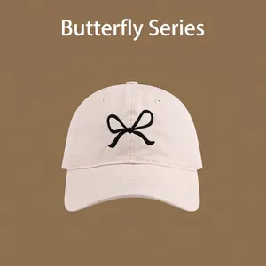 Detail of pink cotton sun hat featuring black butterfly embroidery and UV protection