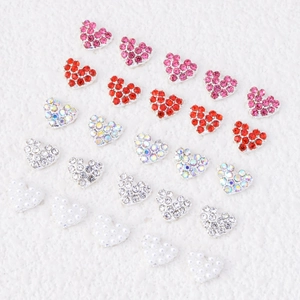 Alloy heart nail charms with rhinestones and pearls on a white textured background