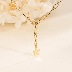Elegante goldene Metallkette mit einem minimalistischen Sternanhänger auf weißem Blumenhintergrund