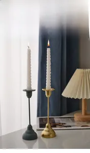 Detail of matte black and brushed gold metal candle holders with white spiral candles