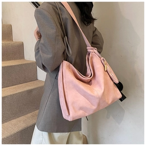 Detail view of pink suede tote bag featuring a matching wide strap and small coin purse charm