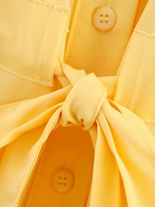 Detail of yellow safari shirt showing twill texture, matching buttons and tie-knot waist