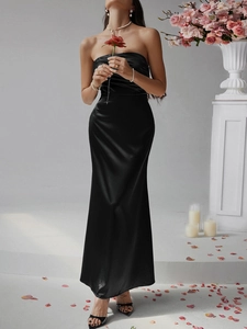 Elegantes, eng anliegendes schwarzes trägerloses Satinkleid mit einer roten Rose im Studio
