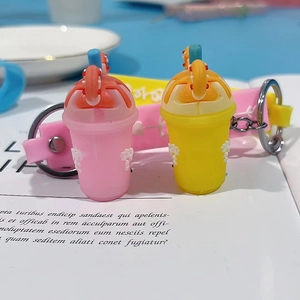 Detailed view of pink and yellow silicone boba tea cup keychains with cream topping and straps