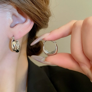 Detail view of silver C-shaped hoop earrings showing the polished finish and clasp design