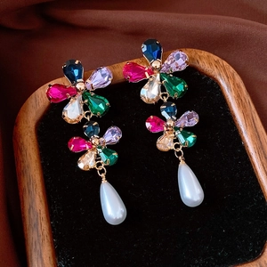 Détail de boucles d'oreilles fleurs en pierres colorées avec perles en forme de goutte