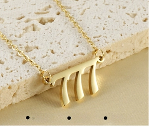 Macro view of gold stainless steel 777 number pendant with a delicate link chain
