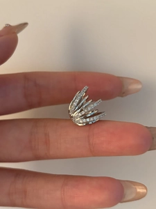 Detail view of silver multi-layer ear cuff with zircon inlay in a hand-held shot