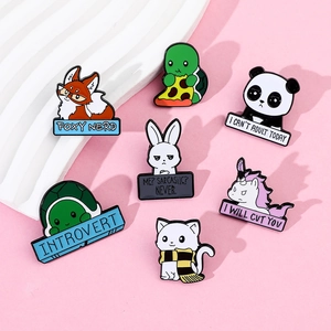 Flat lay of cute cartoon animal metal enamel pins on a pink and white tray
