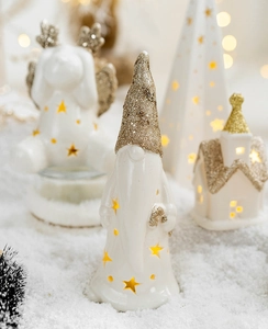 Close-up of glowing ceramic Christmas gnome and church with warm LED star cutouts