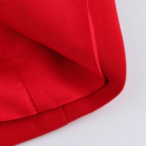 Macro detail of high-density red fabric with precise double-stitched hem and fine texture