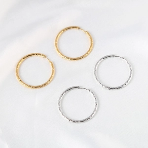 Minimalist gold and silver geometric round hoop earrings on soft white silk fabric