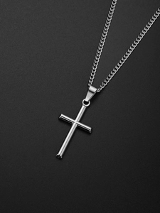 Pendentif croix en argent poli avec chaîne cubaine sur une surface noire texturée