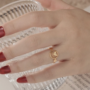 Close-up of a gold butterfly cutout ring on model's hand in an elegant setting