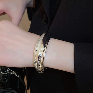 Gros plan d'un bracelet manchette large argenté présentant une surface martelée unique