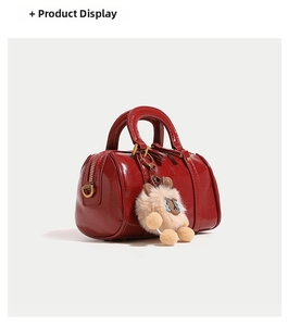 Detail of red Boston bag with textured finish, bronze hardware and plush charm pendant