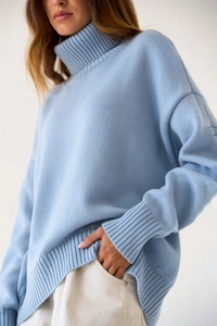 Détail d'un pull en maille grosse bleu ciel avec col roulé et texture côtelée