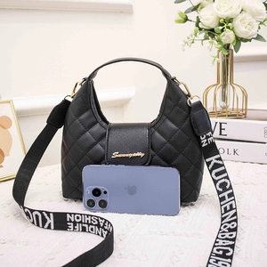 Quilted black PU handbag with wide patterned strap and gold hardware in a chic setting