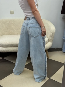 High-waist wide-leg light blue denim jeans with side fringe tassel detail shown from the back