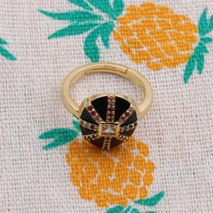Macro shot of gold-plated ring featuring black round disc and colorful zircon stones