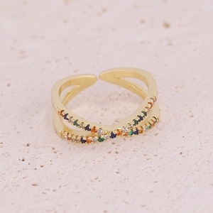 Crossed gold open ring with colorful zircon stars and moon stones on sandstone