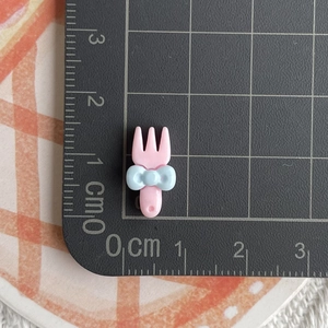 Close-up of a 2cm pink resin fork with blue bow for DIY crafts and phone case decor