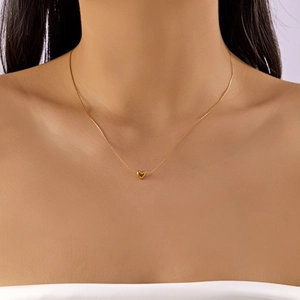Close-up of minimalist 18K gold titanium steel necklace with a tiny heart pendant
